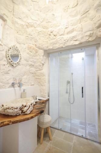 a bathroom with a shower with a glass shower stall at I Trullarelli in Cozzana
