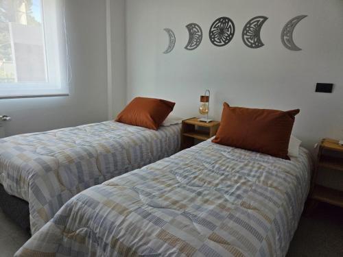 a bedroom with two beds and a moon sign on the wall at Sol del Atardecer in Rada Tilly