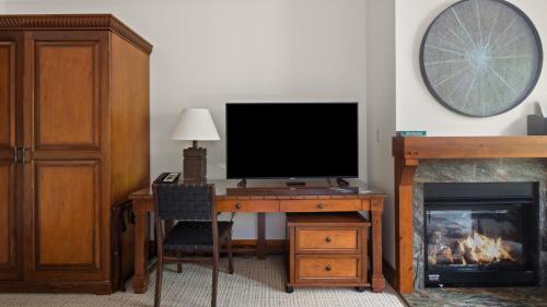 a room with a desk with a television and a fireplace at 1117 Lodge At Spruce Peak Ski In Ski In Ski Out King Studio By Stowe Mountain Rentals in Stowe
