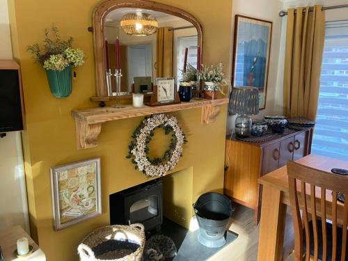 sala de estar con chimenea y espejo en Crispins Corner, en Stedham