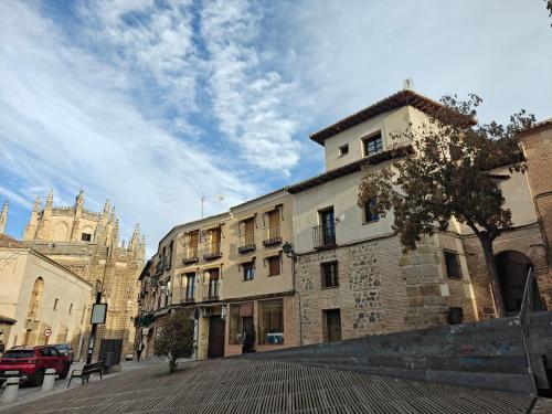 eine Stadtstraße mit einem Gebäude und einer Kathedrale in der Unterkunft Casona Arquillo del Judío in Toledo