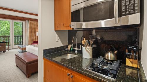 a kitchen with a sink and a microwave above a stove at 1234 Lodge At Spruce Peak Ski In Ski In Ski Out King Studio By Stowe Mountain Rentals in Stowe
