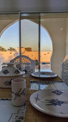 a table with plates and cups on a table with a view of the desert at Djerba Dar Iyad in Mezraya