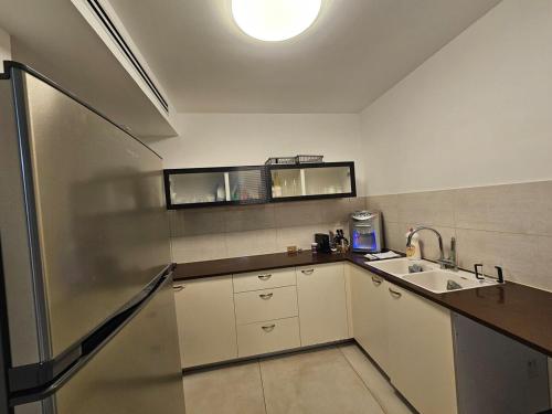 une cuisine avec des armoires blanches et un évier et une lumière dans l'établissement Neveh Shamir Staycation, à Bet Shemesh