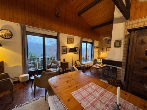 ein Wohnzimmer mit Tisch und Kamin in der Unterkunft Grand chalet de charme cosy, sauna & vue de rêve in Ban-sur-Meurthe-Clefcy