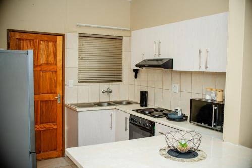 a kitchen with white cabinets and a stove top oven at Villa Ndahafa in Ongwediva
