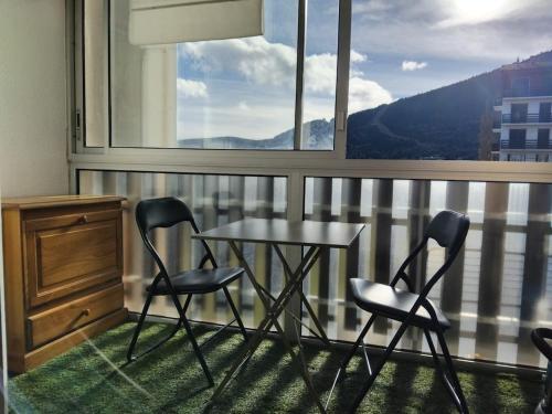 ein Tisch und Stühle in einem Zimmer mit Fenster in der Unterkunft Family Lodge Grand Tetras Les Angles in Les Angles