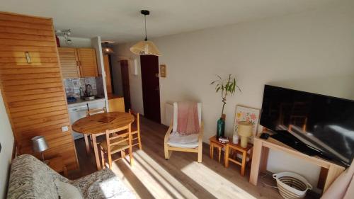 ein Wohnzimmer mit einem Tisch, einem Sofa und einem TV in der Unterkunft Family Lodge Grand Tetras Les Angles in Les Angles