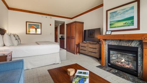 une chambre d'hôtel avec un lit et une cheminée dans l'établissement 1434 - Studio - Spruce Peak Lodge - Stowe Mt Resort - Ski in Ski out - Sleeps 4, à Stowe