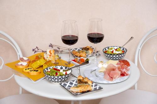カマイオーレにあるBadia Giulia Prestigious Historical B&B, Camaiore - Adults Only - No Petsの赤ワインと食べ物のグラス2杯付きテーブル