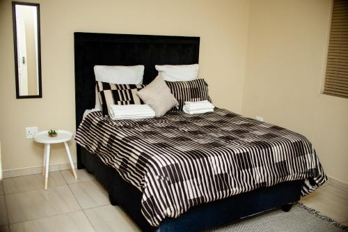 a bed with a black and white comforter and pillows at Villa Ndahafa in Ongwediva