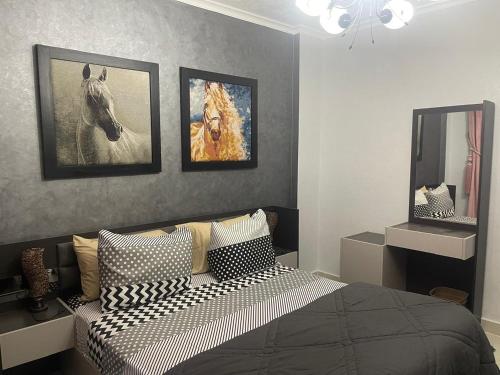 a bedroom with a bed and pictures of a horse on the wall at Cozy Comfort Flat , Madinaty in Cairo