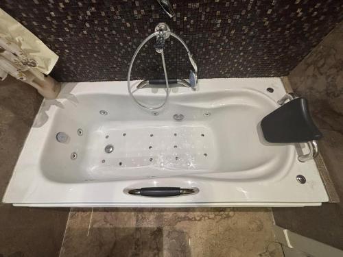 eine weiße Badewanne mit einem Wasserhahn im Bad in der Unterkunft 7 BR Smart House with Heated Pool, Waterfall, Garden in Kairo