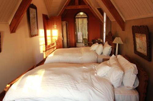 a bedroom with three beds with white sheets at Lokanga Boutique Hotel in Antananarivo