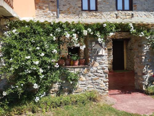 an old stone building with flowers on it at Rincón del Bierzo in Borrenes