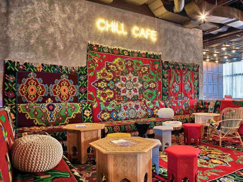 萨拉热窝ibis Styles Sarajevo的一间摆满桌椅的房间，还有一堵墙