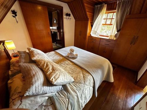 Un dormitorio con una cama con almohadas encima. en Chalé Luxuoso Capivari em Campos do Jordão, en Campos do Jordão