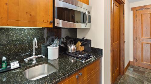 eine Küchentheke mit Spüle und Mikrowelle in der Unterkunft #337 Inside Lodge At Spruce Peak Studio Ski in in Ski out By Stowe Mountain Rentals in Stowe