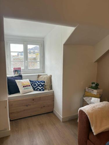 Cette chambre comprend un banc avec des oreillers et une fenêtre. dans l'établissement Charmant appartement - Le Dopamine, à La Roche-sur-Yon
