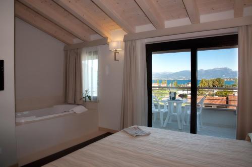 a bedroom with a bed and a view of a balcony at Hotel Porto Azzurro in Sirmione