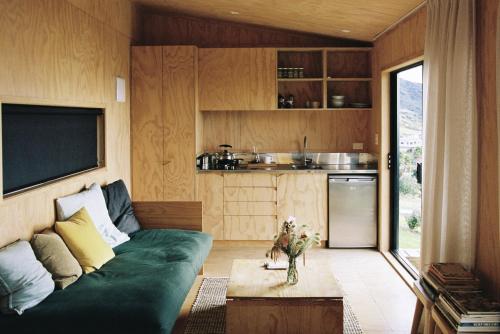 a living room with a green couch and a kitchen at The Huts in Ahipara