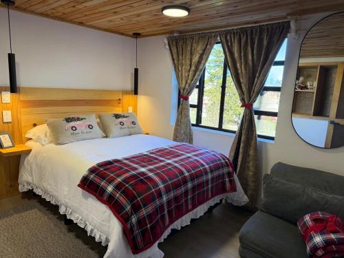 a bedroom with a bed and a couch and a window at El Sótano Loft in Tlalpujahua de Rayón