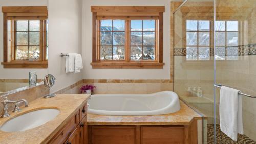 a bathroom with a tub and a sink at STOWE GLOBE 4 BEDROOM LUXURY CABIN SKI IN SKI OUT By Stowe Mountain Rentals in Stowe