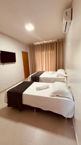 a hotel room with two beds and a flat screen tv at Casa 3 suítes Salinas in Salinópolis