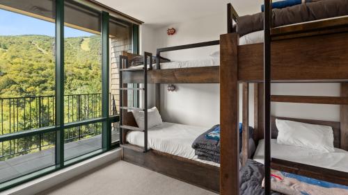 une chambre avec lits superposés et un balcon avec vue dans l'établissement New Spruce Peak Tree House Unit Steps To The Lifts With Big Mountain Views Sleeps 9 By Stowe Mountain Rentals, à Stowe