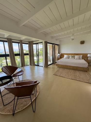 a bedroom with a bed and a chair and windows at Kainos Tropical Boutique Hotel in Las Terrenas