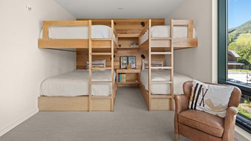 Cette petite chambre comprend des lits superposés et une chaise. dans l'établissement 411 Spruce Peak Stowe Mountain Resort New Treehouse unit Ski in Ski out 4 bed sleeps 12, à Stowe Mountain