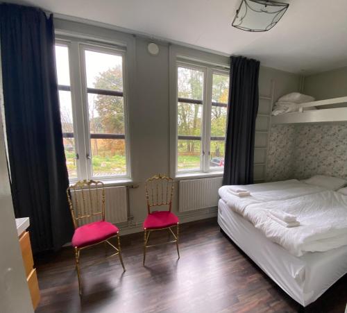 a bedroom with two chairs and a bed and windows at Kungälvs Bed & Brekfast in Kungälv