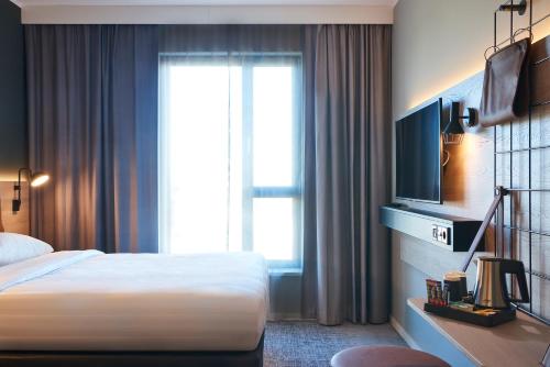 a hotel room with a bed and a large window at Moxy Birmingham NEC and Airport in Bickenhill
