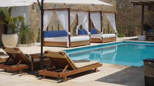 ein Schwimmbecken mit vier Betten und Stühlen neben einem Schwimmbecken in der Unterkunft Hotel Estrella de Mar in Zipolite