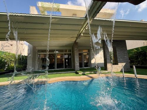 einem Pool vor einem Gebäude mit Wasser in der Unterkunft 7 BR Smart House with Heated Pool, Waterfall, Garden in Kairo