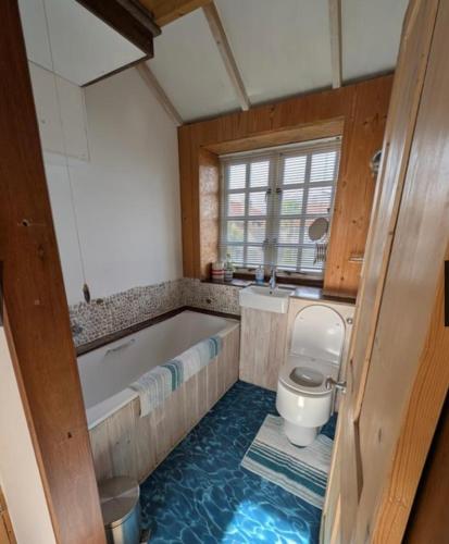 a bathroom with a tub and a toilet at Cowes View Seaside beach cottage, in Hill Head