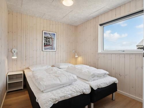 a bedroom with a bed with white sheets and a window at 5 star holiday home in Idestrup in Marielyst