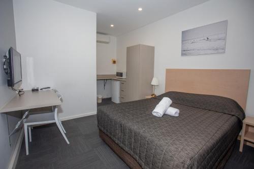 ein Schlafzimmer mit einem Bett, einem Schreibtisch und einem Fernseher in der Unterkunft Westside Motor Inn in Sydney