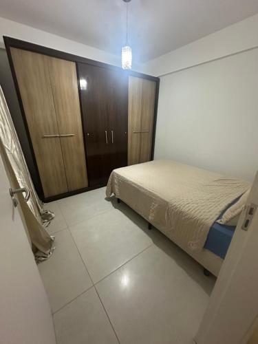 a bedroom with a bed and a wooden cabinet at Apartamento de 2 quartos equipado em Imbituba sc in Imbituba