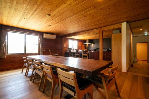 a dining room with a large wooden table and chairs at みみずく山荘 Mimizuku Lodge in Myoko