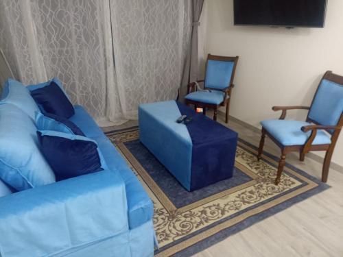 un salon avec un canapé bleu et deux chaises dans l'établissement Departamento para 6 personas, à Iquique