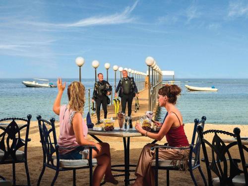 Un groupe de personnes assises à une table sur la plage dans l'établissement Movenpick Resort El Quseir, à Al-Qusair