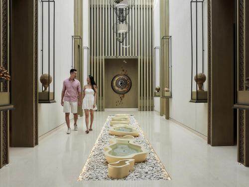 Ein Mann und eine Frau gehen einen Flur entlang, in dem sich eine Reihe von Toiletten befindet. in der Unterkunft Mövenpick Resort & Spa Jimbaran Bali in Jimbaran