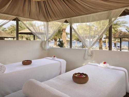 two beds in a room with a view of the beach at Mövenpick Resort & Spa Tala Bay Aqaba in Aqaba