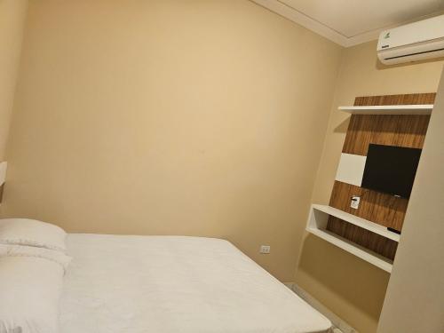 a small room with a bed and a tv at Urban Center Apartamentos in Salto del Guairá