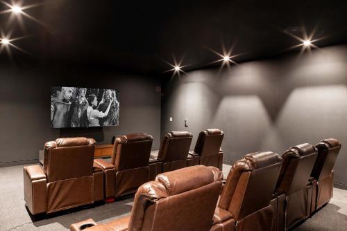 a cinema room with leather chairs and a flat screen tv at Brightwater by Rove Sauna Pool & Outdoor Spaces in Freetown