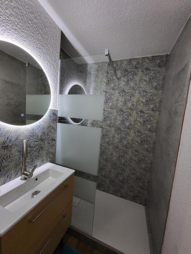 ein Badezimmer mit Waschbecken und Spiegel in der Unterkunft Le Panoramic in Thollon