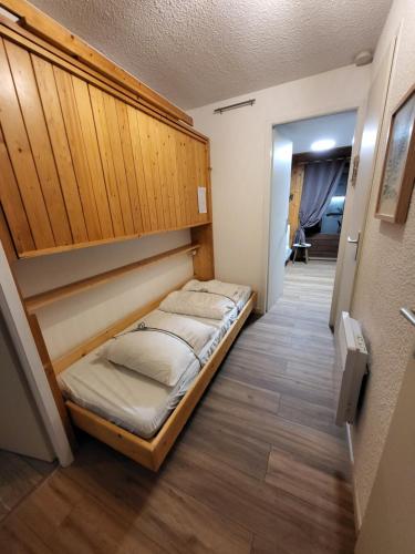 Bett in einem Zimmer mit einem Kopfteil aus Holz in der Unterkunft Le Panoramic in Thollon