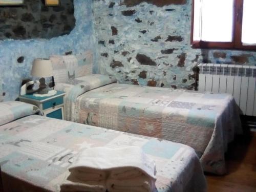 a room with three beds and a stone wall at Rincón del Bierzo in Borrenes
