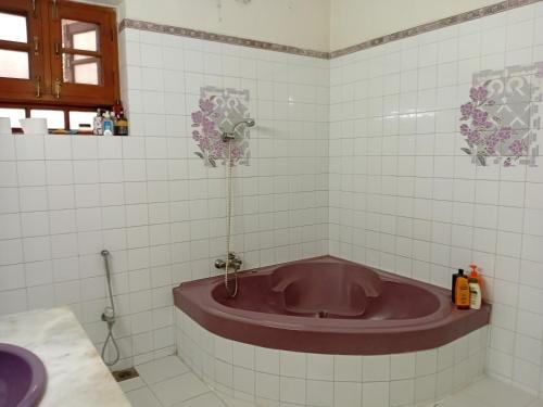 un bagno con una vasca viola nell'angolo di Naim Ullah Tiwana a Lahore